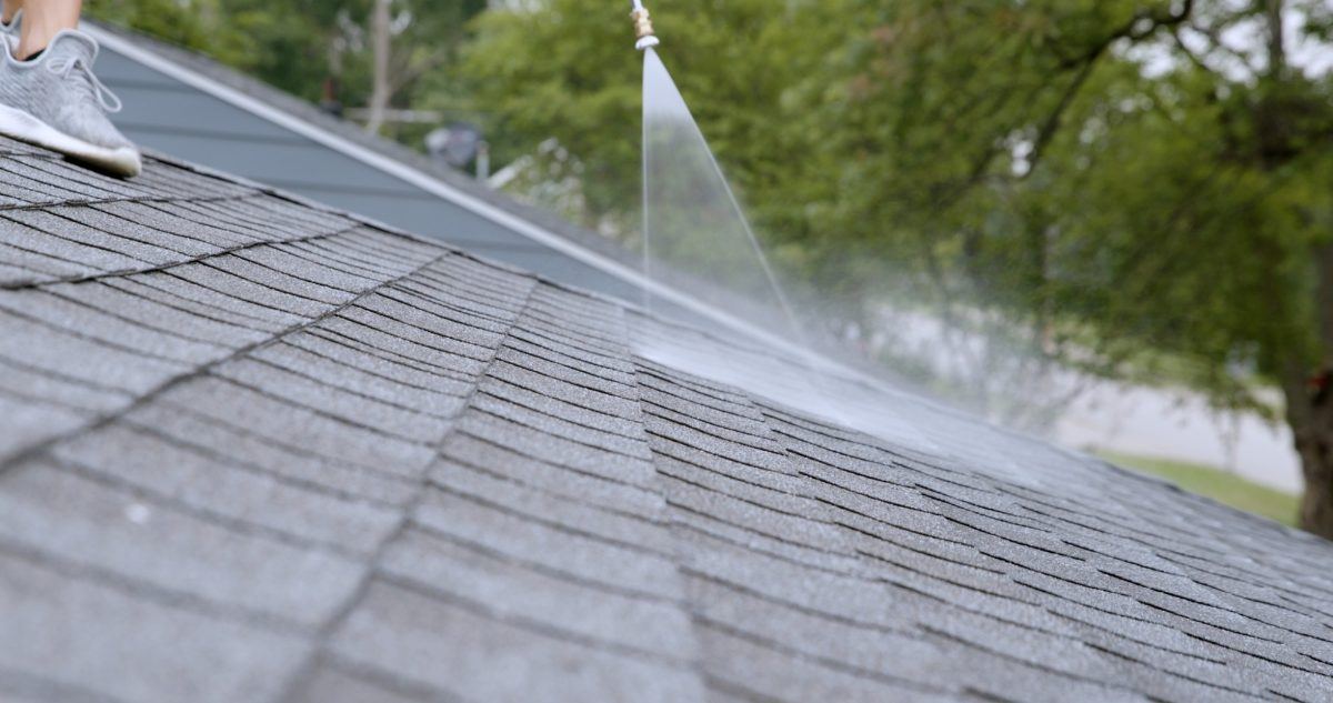 Close-up of a fine spray of treatment landing on asphalt shingles